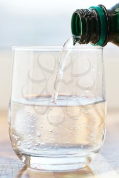 spring water pouring into glass from green bottle
