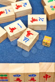 wooden tiles in mahjong game during playing on blue cloth table close up