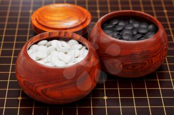 black and white double convex yunzi stones in wooden bowl on go board