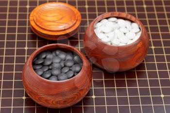 black and white go game stones in wooden bowl