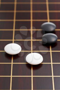black and white stones during go game playing on goban close up