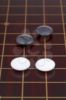 four stones during go game playing on dark wood goban
