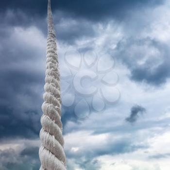 rope rises to dark sky with storm clouds