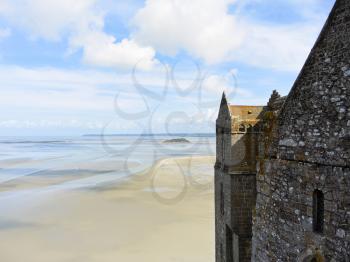 scenic with Tombelaine island and tidal bay at low tide and wall of mont saint-michel abbey, Normandy