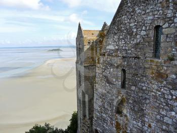 view of Tombelaine island and tidal bay at low tide and wall of mont saint-michel abbey, Normandy
