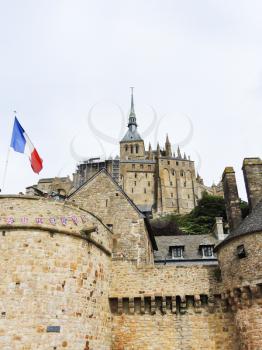 flag, stone walls and abbey mont saint-michel in Normandy, France