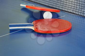 two paddle, tennis ball on blue ping pong table close up