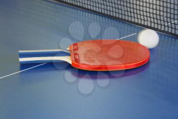 red racket, tennis ball on blue ping pong table close up