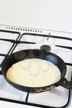 baking pancake on frying pan on gas stove