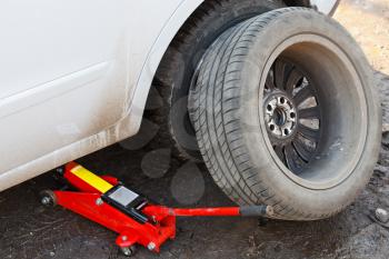 seasonal replacement of tires with jack outdoors - lifting car by hydraulic jack