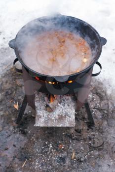food stewed in cauldron on mobile brazier outdoors in winter