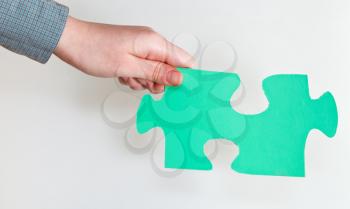 green puzzle piece in female hand on grey background