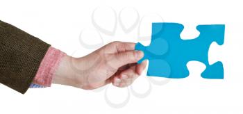 male hand holding big blue paper puzzle piece isolated on white background