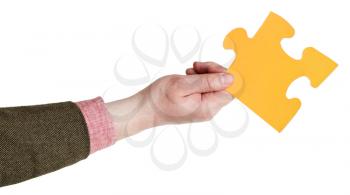 male hand holding big yellow paper puzzle piece isolated on white background
