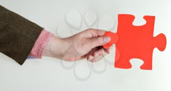 red puzzle piece in male hand on grey background