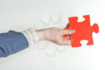 red puzzle piece in male hand on grey background