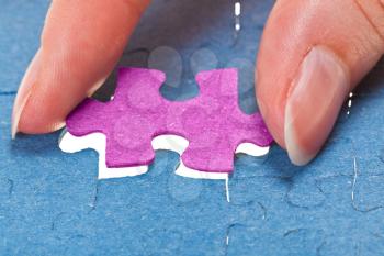 inserting the last pink piece of puzzle in free space in assembled jigsaw puzzles