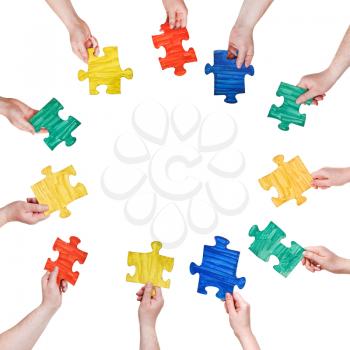 set of painted puzzle pieces in people hands in circle isolated on white background
