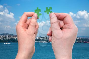 male and female hands with little puzzle pieces with sea and Istanbul waterfront background