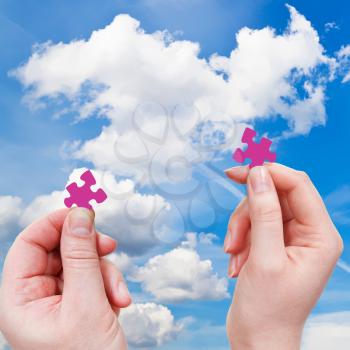 male and female hands with little puzzle pieces with white cloud and blue sky background
