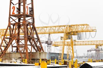 tower and gantry cranes in open air metal product warehouse