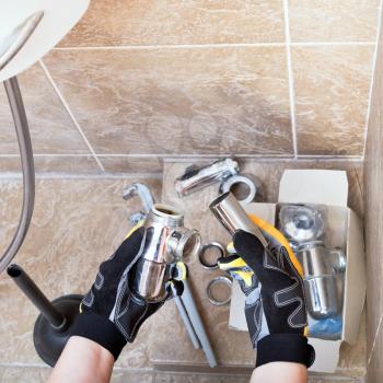 Sanitary technician repairs plumbing trap from sink in bathroom