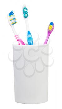 one children and two adult tooth brushes in ceramic glass - family set of toothbrushes isolated on white background