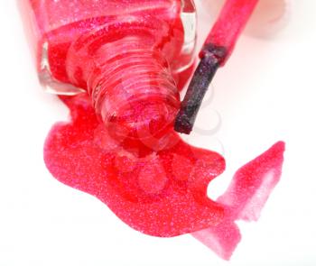 bottle with spilled red nail polish close up on white background