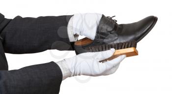 Shoeshiner in white gloves brushing black shoe by brush isolated on white background
