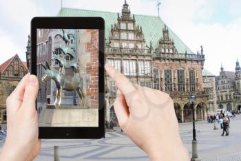 travel concept - tourist taking photo of Bremen Town Musicians statue on mobile gadget, Germany