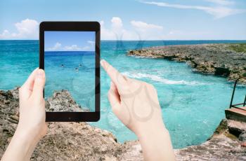 travel concept - tourist taking photo of stone coastline of Caribbean Sea in Bay of Pigs of on mobile gadget, Cuba