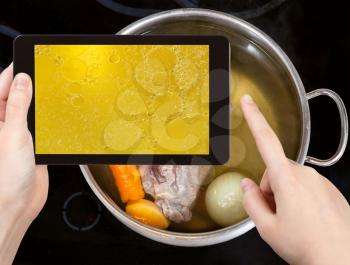 photographing food concept - tourist taking photo of boiling beef broth with with seasoning vegetables on mobile gadget