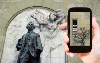 travel concept - tourist taking photo of walls and statue of Major Davel in Chateau Saint-Maire in Lausanne, Switzerland on mobile gadget