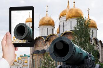 travel concept - tourist taking photo of Tsar Cannon and gold cupola of Cathedrals in Moscow Kremlin on mobile gadget, Russia
