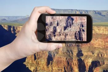 travel concept - tourist taking photo of rocky mountains in Grand Canyon on mobile gadget, Nevada, USA