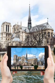 travel concept - tourist taking photo of cathedral Notre-Dame de Paris and Seine River in spring on mobile gadget, France