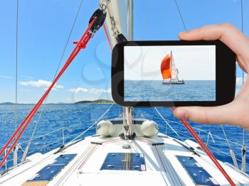 travel concept - tourist taking photo of red yacht in blue Adriatic sea, Dalmatia, Croatia on mobile gadget