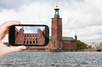 travel concept - tourist taking photo of courtyard Stockholm City Hall, Sweden on mobile gadget