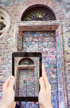 travel concept - tourist taking photo of door of Juliet House (Casa di Giulietta) in Verona on mobile gadget, Italy