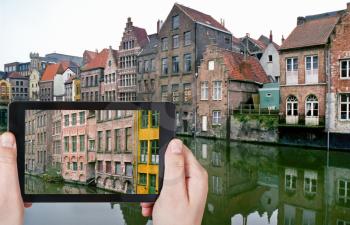 travel concept - tourist taking photo of old houses in Ghent city on mobile gadget, Belgium