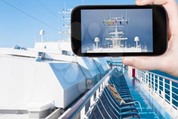 travel concept - tourist takes picture of flags of european countries on navigation antenna of cruise liner on smartphone,