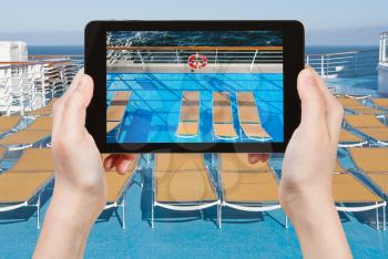 travel concept - tourist takes picture of sunbath chairs on side of cruise line on smartphone,