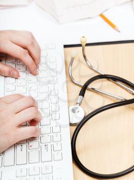 physician works on white PC keyboard close up