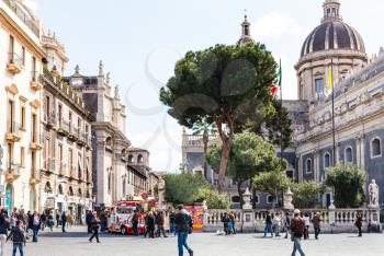 CATANIA, ITALY - APRIL 5, 2015: people on Piazza del Duomo and Saint Agatha Cathedral in Catania, Sicily, Italy. The fountain was assembled in 1736 by Giovanni Battista Vaccarini.