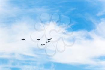 flight of military fighter airplanes in white clouds in blue sky