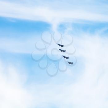 four military fighter jets in cloudy blue sky