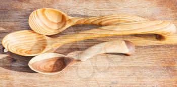 three carved wooden spoons on cutting board