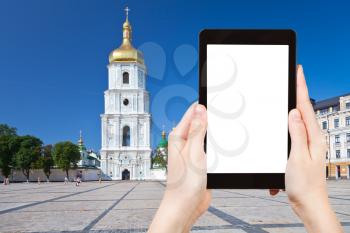 travel concept - tourist photograph bell tower and Saint Sophia Cathedral through Sophia square in Kiev, Ukraine on tablet pc with cut out screen with blank place for advertising logo
