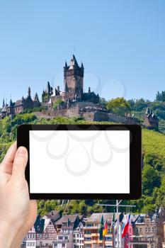 travel concept - tourist photograph castle over town Cochem on Moselle river bank in Germany on tablet pc with cut out screen with blank place for advertising logo