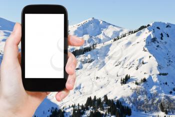 travel concept - tourist photograph snowy peaks of Alps mountains in Portes du Soleil region, Morzine - Avoriaz, France on tablet pc with cut out screen with blank place for advertising logo